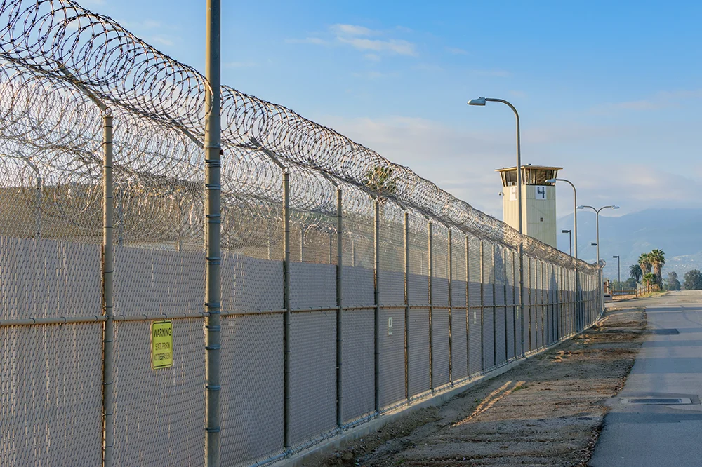 Prison perimeter fence with razor wire and guard tower